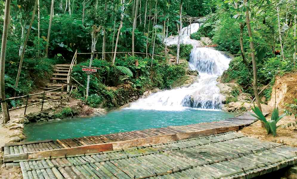 Pemandangan menakjubkan dari air terjun Taman Sungai Mudal yang jernih dan segar mengalir di antara bebatuan besar