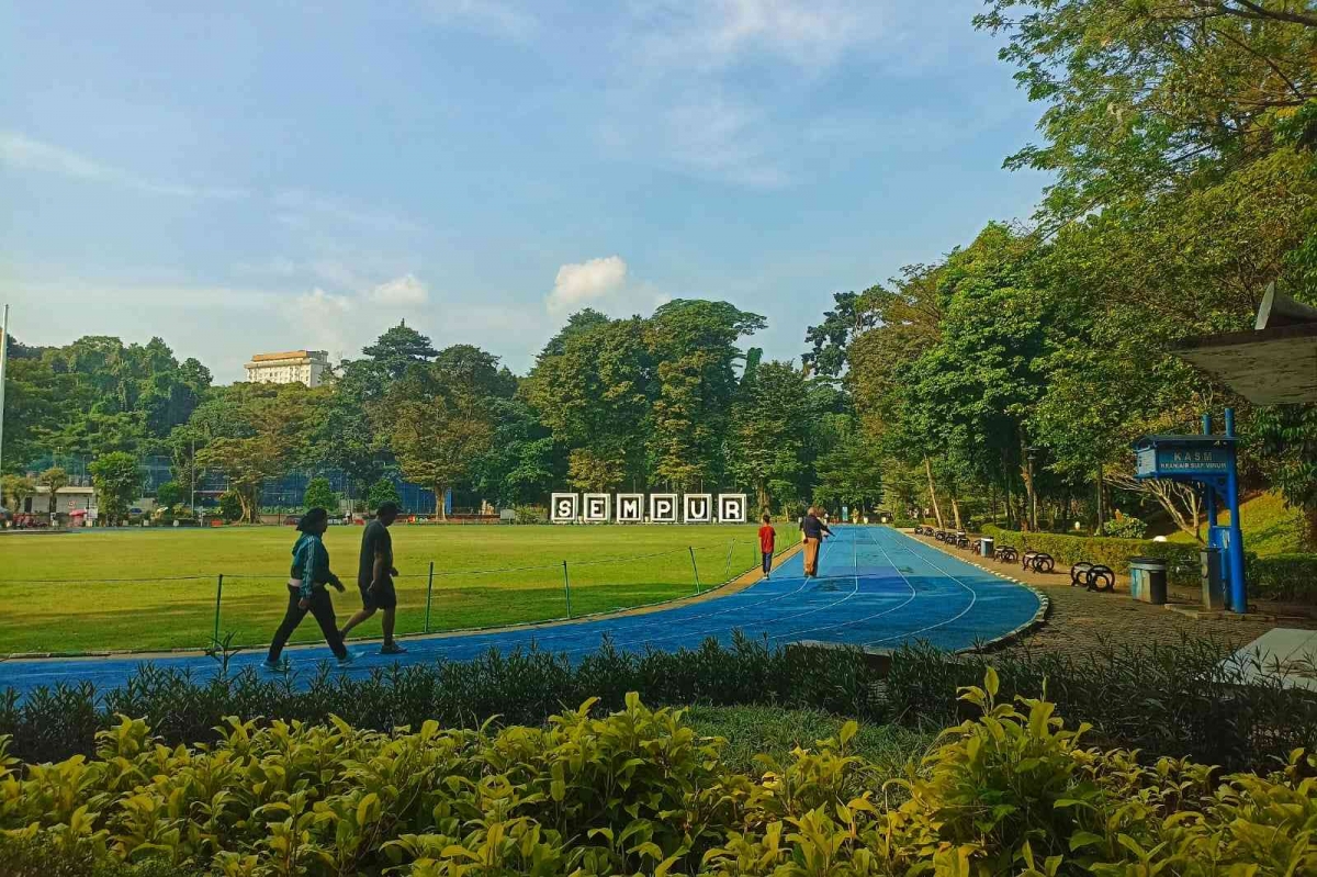 Lapangan hijau dan lintasan biru Sempur dengan pepohonan di Kota Bogor